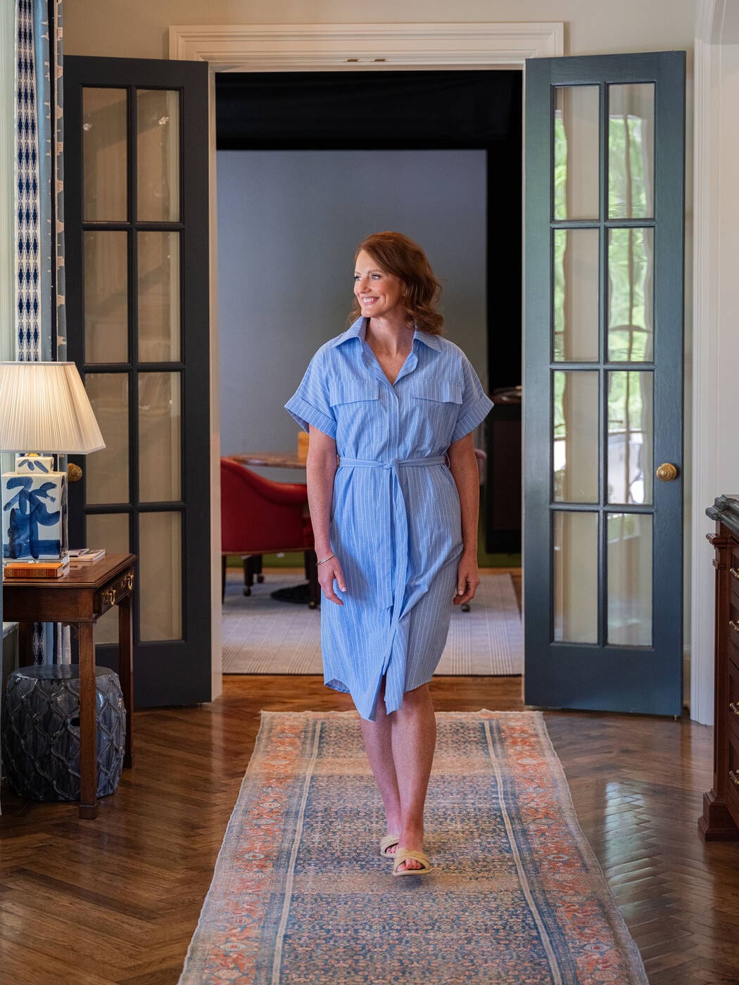 brand photography of a woman in blue dress walking down a hall on a pink and blue carpet