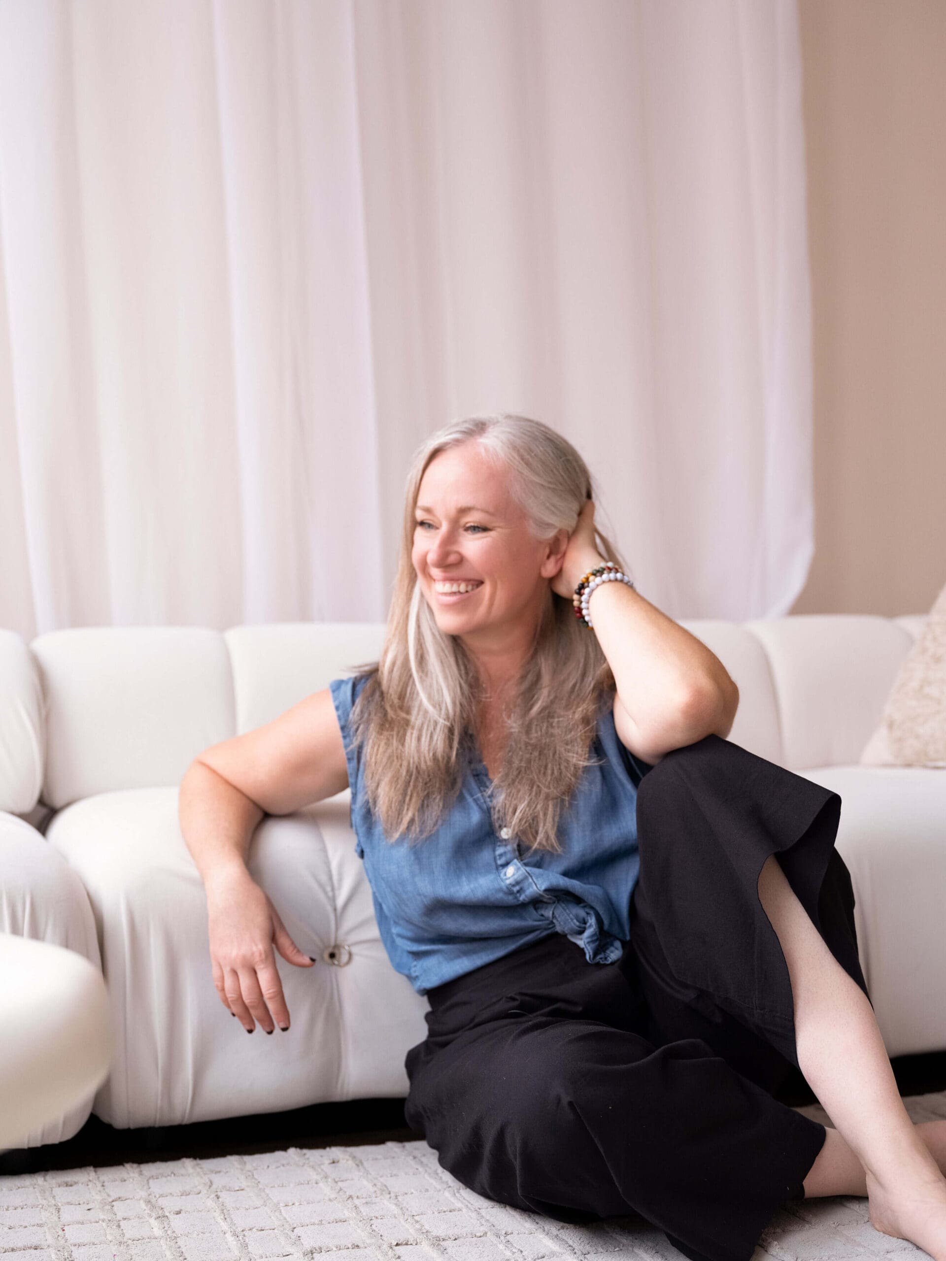 Jama Finney laughing during a candid studio portrait session, Louisville brand photographersilver haired woman sitting in front of a white couch smiling